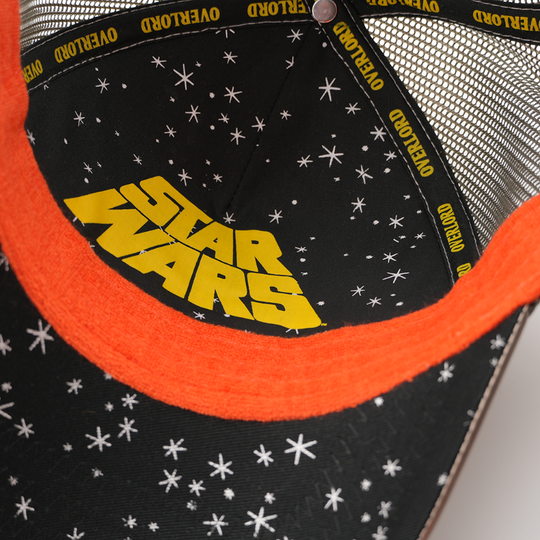 Underside of the IG-88 trucker cap showing a starry black brim print with yellow Star Wars logo, orange trim, gray mesh crown, and yellow Overlord taping.