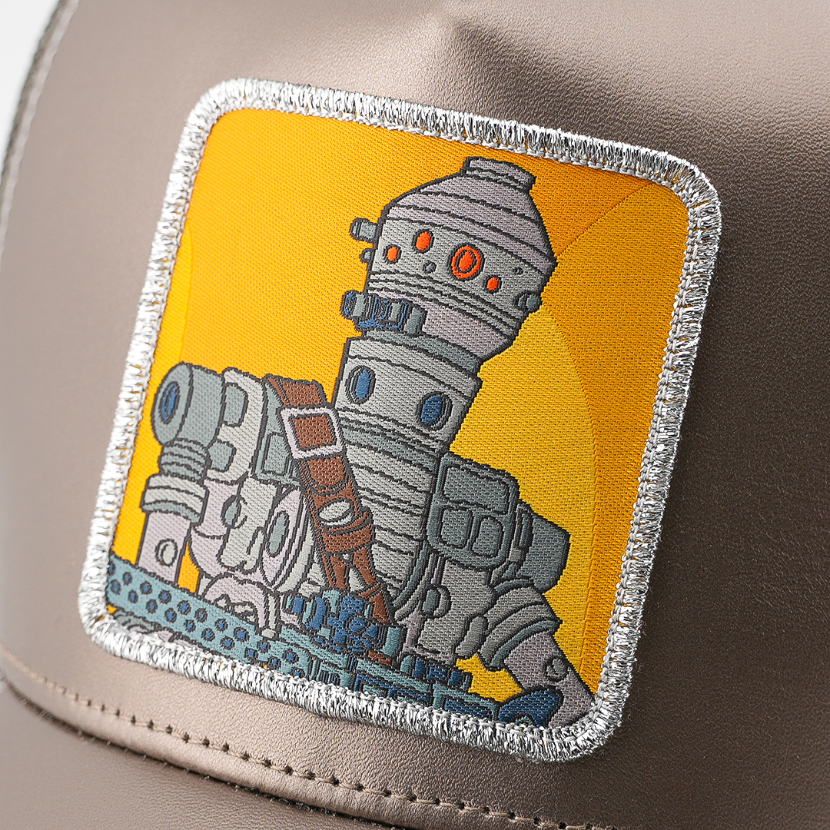 Close-up of the IG-88 from Star Wars patch on a yellow background, stitched onto the metallic gray trucker cap fabric with silver border.