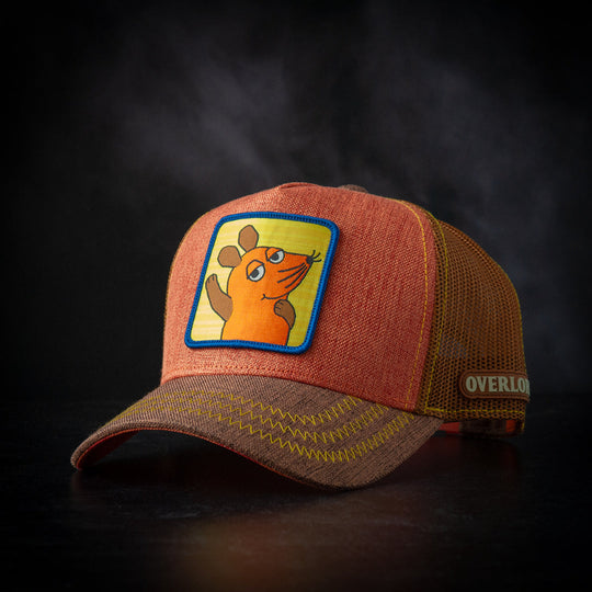 Orange and brown cap with a cartoon Die Maus patch on a dark background