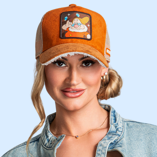 Model wearing the orange suede-textured Doc from Disney's Snow White and the Seven Dwarfs retro trucker cap with a brown brim and tan mesh side.