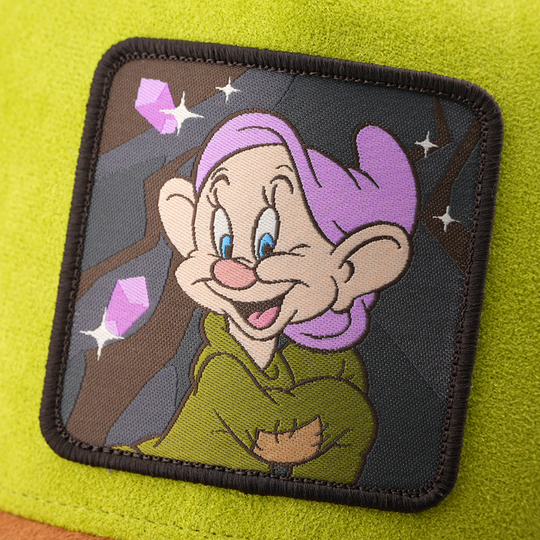 Woven patch of Dopey from Disney's Snow White and the Seven Dwarfs smiling against a mine and gem-themed background, with a black border, stitched onto the green suede-textured retro trucker cap.
