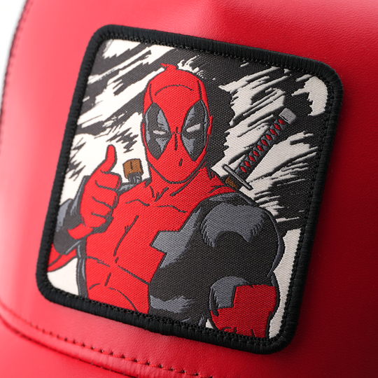 Close-up of a woven Marvel's Deadpool patch giving a thumbs-up with a black border, stitched onto glossy red cap fabric.