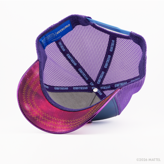 Underside of the Evil-Lynn from Masters of the Universe retro trucker cap, showing a pink and purple starry-print brim, blue Masters of the Universe tag, purple mesh crown, and purple Overlord branded taping with blue text.