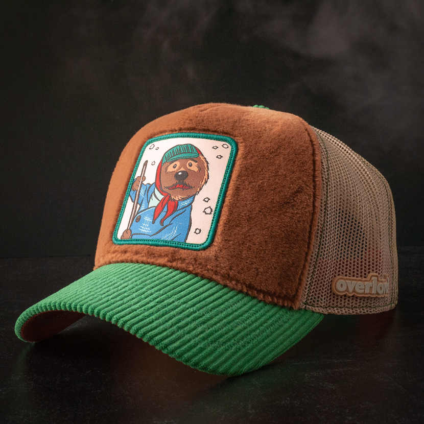 Brown faux fur trucker cap with green corduroy brim and khaki mesh featuring a woven patch of Emmet the Otter from Emmet Otter attached to the crown.