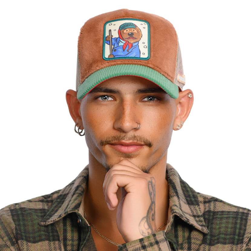 Man wearing brown faux fur trucker cap with green corduroy brim and khaki mesh featuring a woven patch of Emmet the Otter from Emmet Otter attached to the crown.