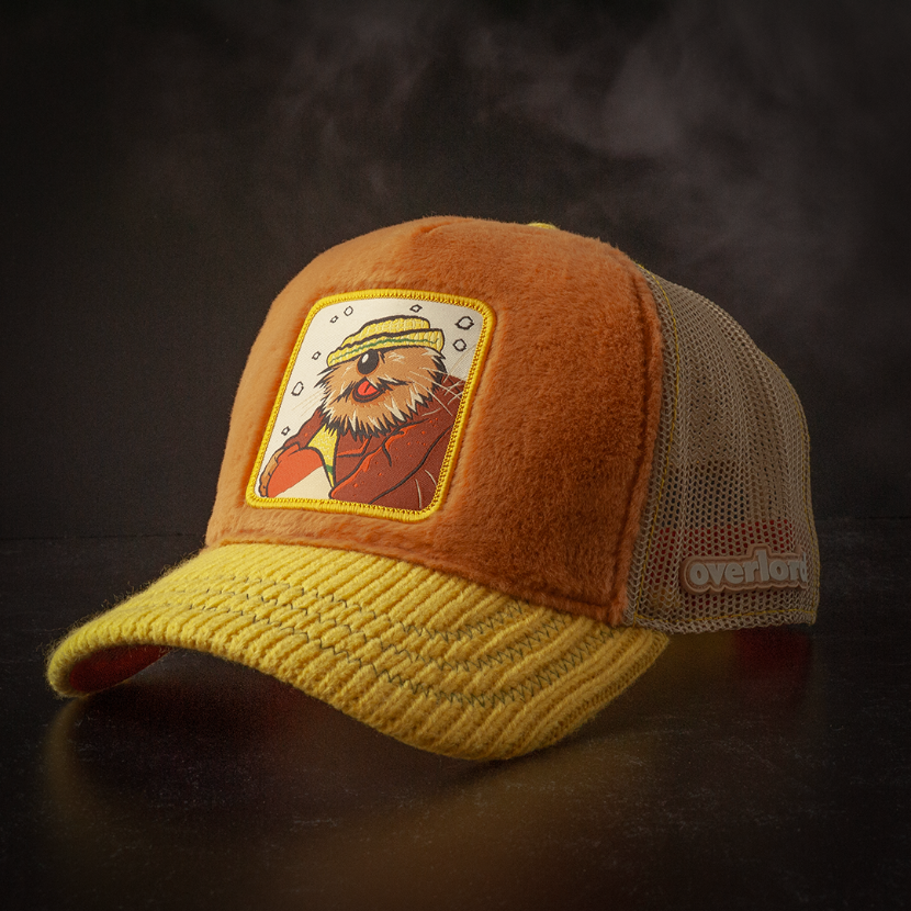Brown faux fur trucker cap with yellow sweater knit brim and khaki mesh featuring a woven patch of Wendell the Porcupine from Emmet Otter attached to the crown.