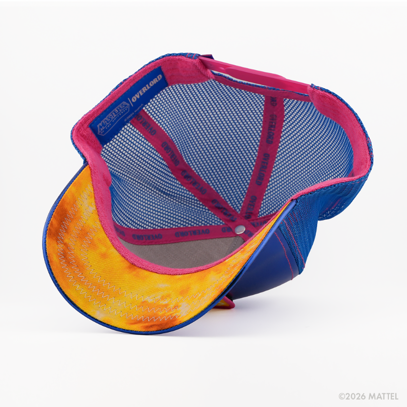 Underside of the Man-E-Faces from Masters of the Universe retro trucker cap, showing a yellow weathered-texture brim, blue Masters of the Universe tag, blue mesh crown, and pink Overlord branded taping with blue text.