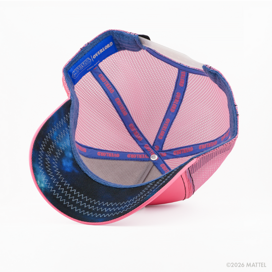 Underside of the Faker from Masters of the Universe retro trucker cap, showing a navy starry-print brim, blue Masters of the Universe tag, pink mesh crown, and blue Overlord branded taping with red text.
