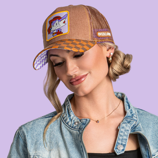 Model wearing the brown Fang from Sonic the Hedgehog retro trucker cap, with checkered brim and purple and brown mesh sides.