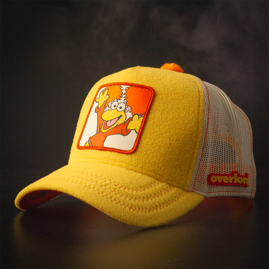 Yellow fleece trucker cap hat with Fraggle Rock Red woven patch against black background