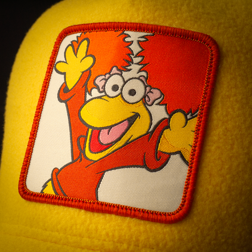 Close-up of Fraggle Rock Red woven patch on yellow fleece trucker cap hat 