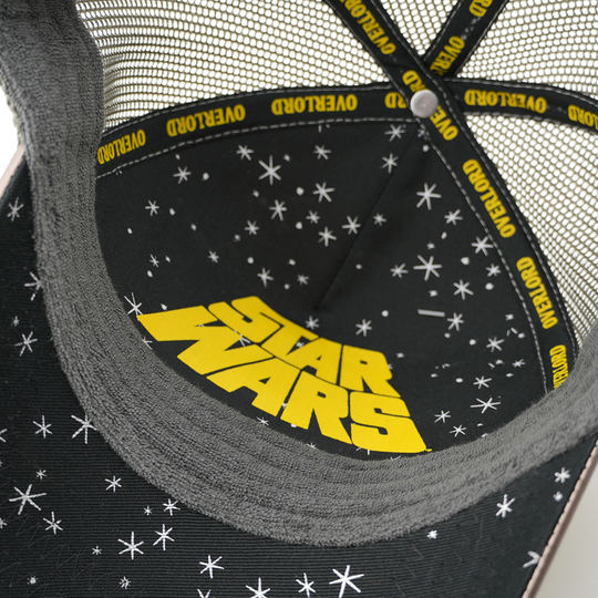 Underside of the Gamorrean Guard trucker cap showing a starry black brim print with yellow Star Wars logo, gray mesh crown, and yellow Overlord taping.