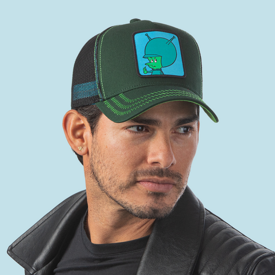 Man wearing forest green OVERLORD X Flintstones Great Gazoo trucker baseball cap hat with green zig zag stitching. PVC Overlord logo.