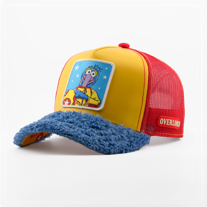 Yellow retro trucker cap with a fuzzy-textured blue brim and a patch of Gonzo from The Muppets in a superhero costume on a star-print blue background, red mesh back with tan Overlord logo.