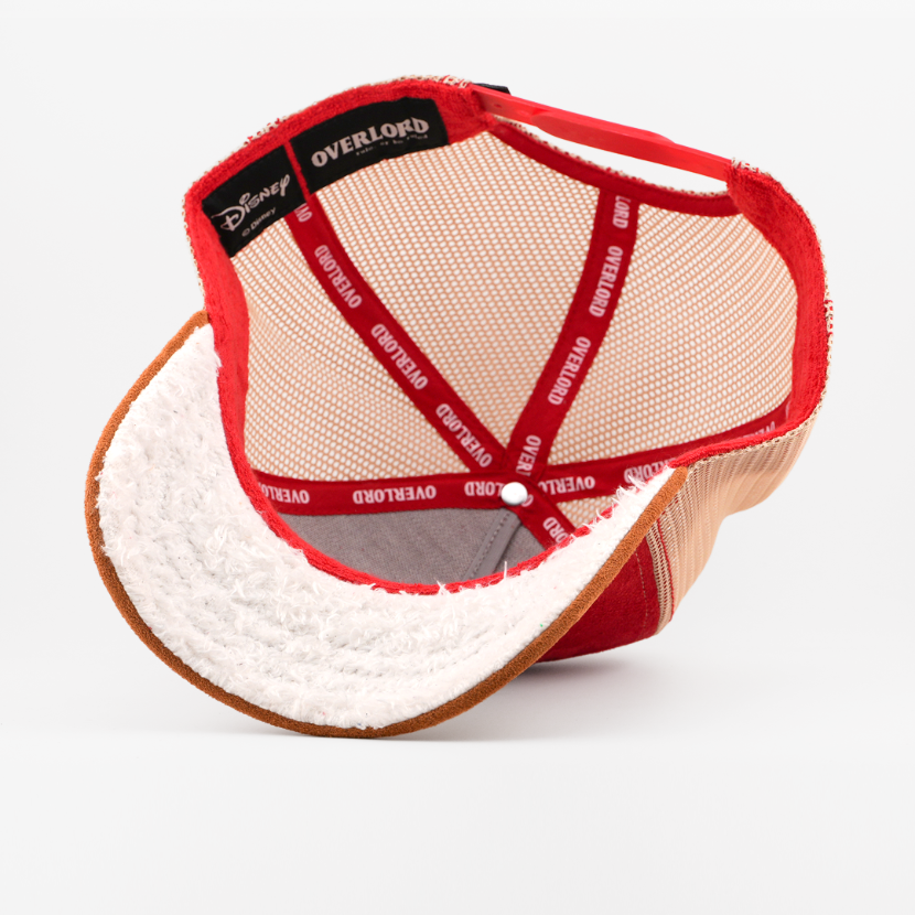 Underside of the Grumpy from Disney's Snow White and the Seven Dwarfs retro trucker cap showing a white fuzzy-textured brim, a Disney tag, tan mesh crown, and red Overlord branded taping.