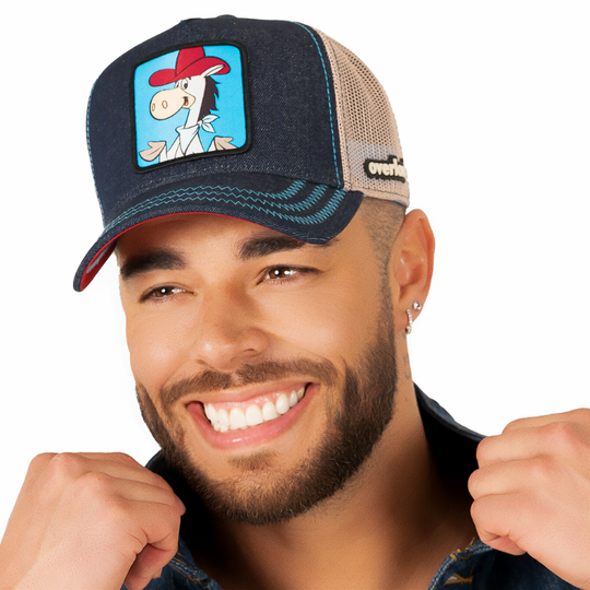 Man wearing dark blue denim trucker cap with khaki mesh featuring a woven patch of Quick Draw McGraw from the classic Hanna-Barbera cartoons attached to the crown.