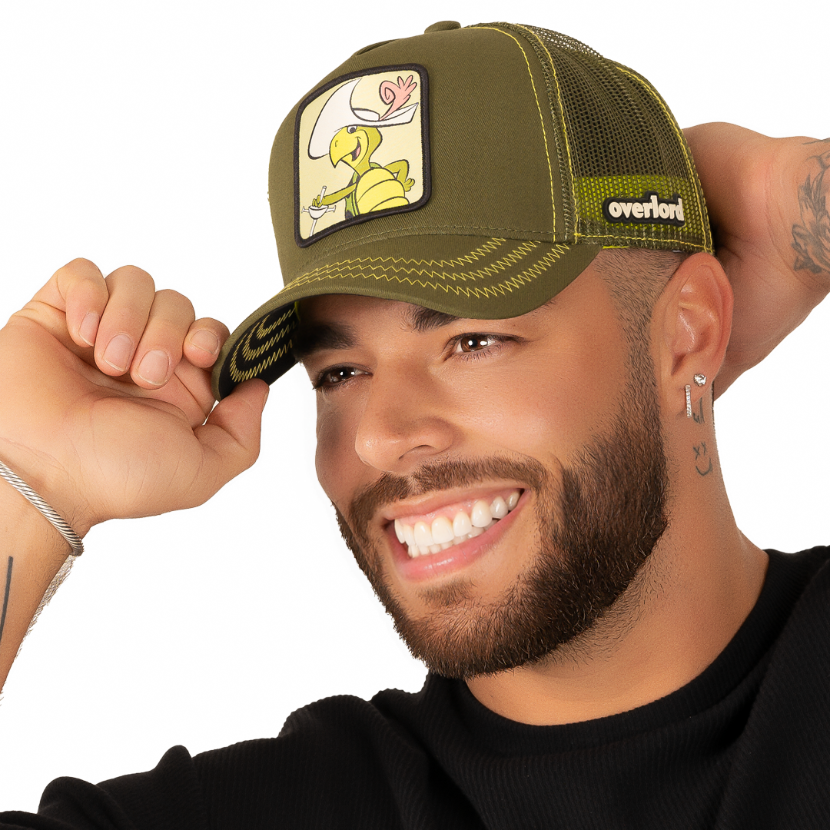 Man wearing olive green twill trucker cap with olive green mesh featuring a woven patch of Touché Turtle from the classic Hanna-Barbera cartoons attached to the crown.