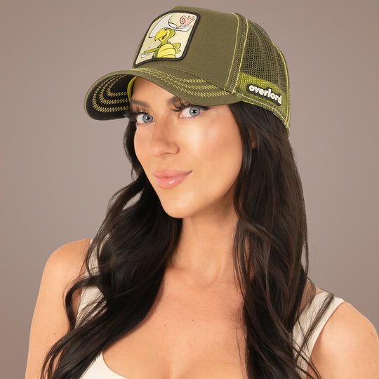 Woman wearing a green cap with a cartoon character and brand logo on a beige background