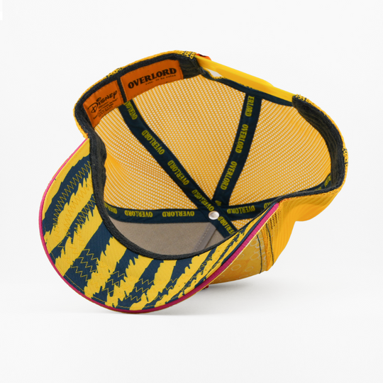 Underside of the Heffabee trucker cap showing a black and yellow striped brim, Disney tag, yellow mesh crown, and yellow Overlord taping.