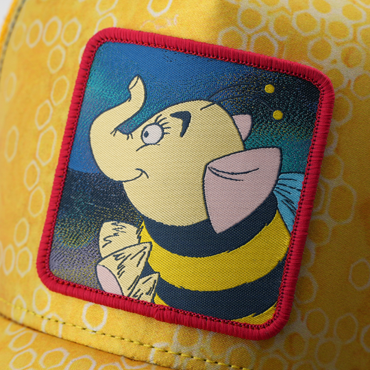 Close-up of the Heffabee patch against a night sky background, stitched onto the yellow honeycomb-print trucker cap fabric.