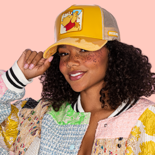 Woman wearing a yellow cap with a cartoon character on a pink background