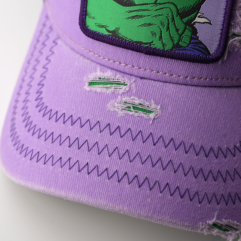 Close-up of the purple cap's distressed brim showing torn fabric details and zigzag stitching below the Hulk patch.