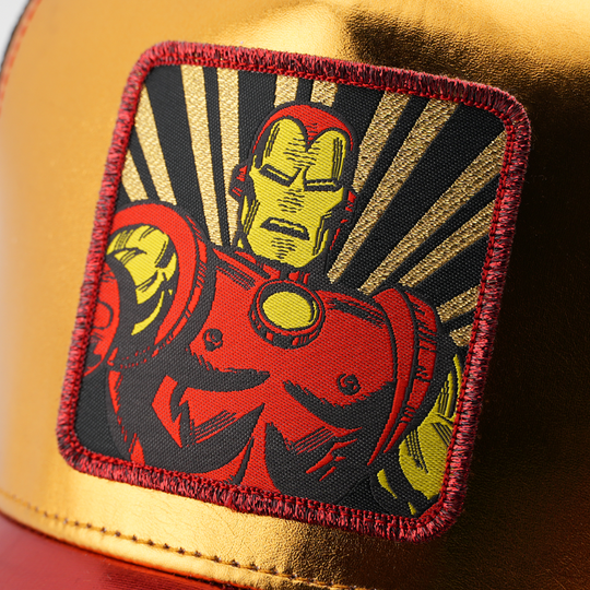 Close-up of a woven Marvel's Iron Man patch with radiating gold rays, stitched onto metallic gold cap fabric.
