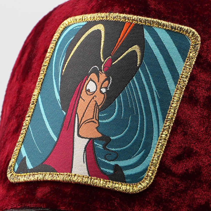 Close-up of Jafar from Disney's Aladdin patch against a swirling blue background, stitched onto the maroon velvet retro trucker cap fabric with gold border.