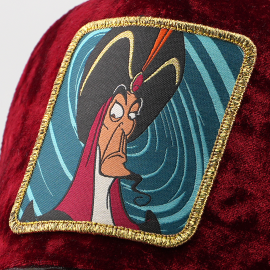 Close-up of Jafar from Disney's Aladdin patch against a swirling blue background, stitched onto the maroon velvet retro trucker cap fabric with gold border.