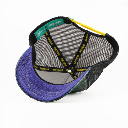 Underside of the Kaa from Disney's The Jungle Book retro trucker cap showing a purple snakeskin-textured brim, black mesh crown, Disney tag, and black Overlord branded taping with yellow text.