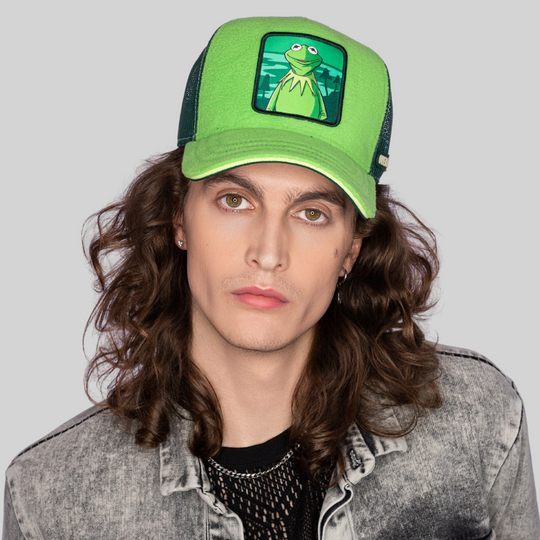 Model wearing the lime green Kermit the Frog from The Muppets retro trucker cap with a yellow-edged brim and dark green mesh side.