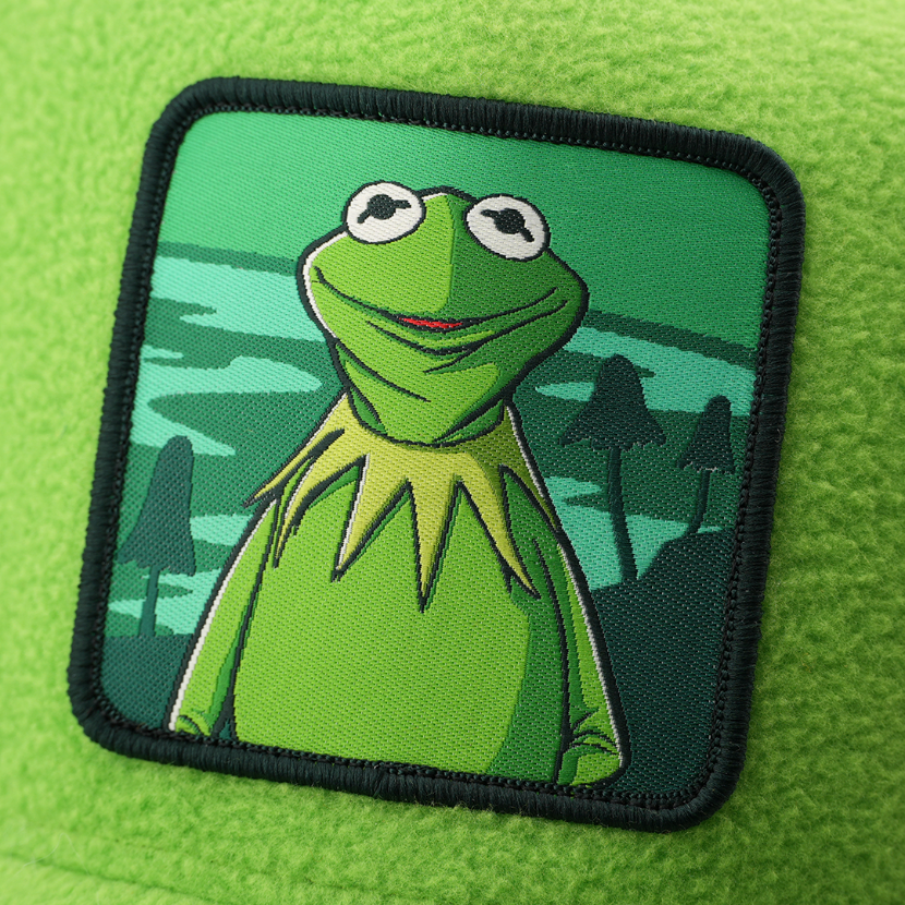 Close-up of a woven patch showing Kermit the Frog from The Muppets by a swamp with silhouetted trees, stitched onto lime green fabric with a black border.