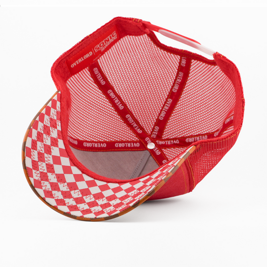 Underside of the Knuckles from Sonic the Hedgehog retro trucker cap, showing a red and white argyle-pattern brim, Sonic the Hedgehog tag, grey mesh crown, and red Overlord branded taping with white text.