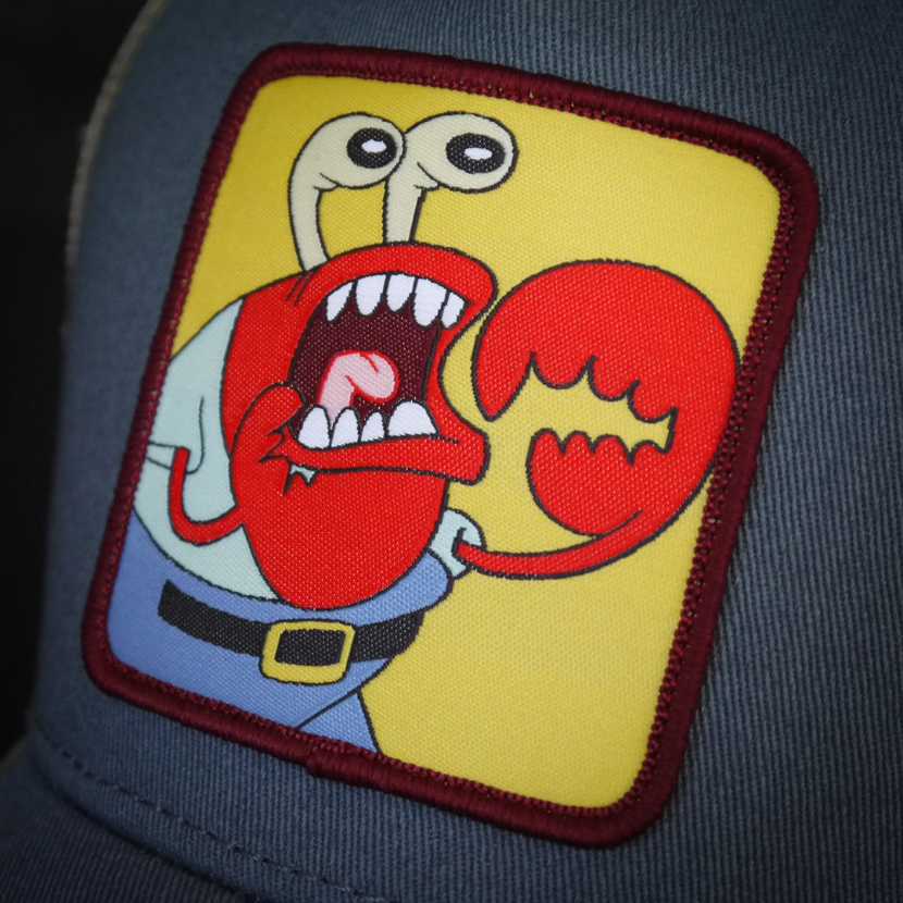 Steel Blue OVERLORD X SpongeBob choking Krusty Krab trucker baseball cap hat woven Overlord patch closeup.