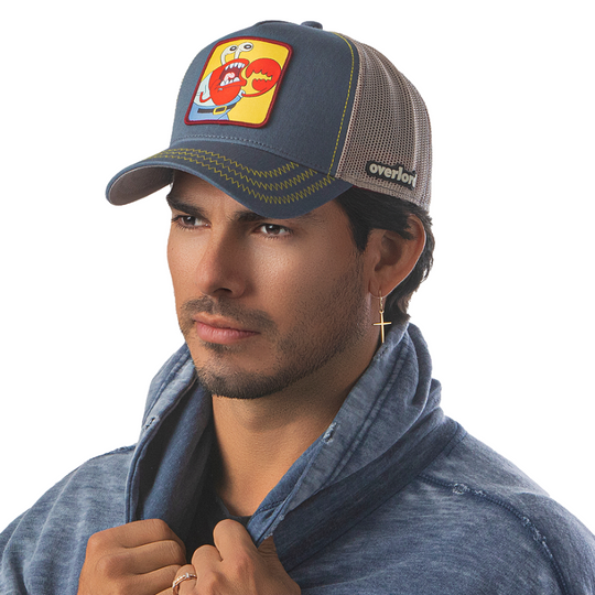 Man wearing steel blue OVERLORD X SpongeBob choking Krusty Krab trucker baseball cap hat with yellow zig zag stitching. PVC Overlord logo.