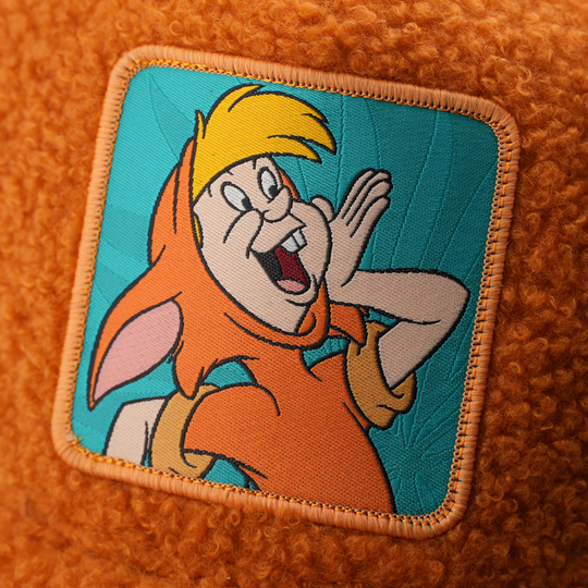 Close-up of a woven patch showing Lost Boy Slightly from Disney's Peter Pan shouting with a hand cupped to his mouth on a teal background, stitched onto fuzzy-textured burnt orange fabric with an orange border.