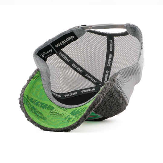 Underside of the First Twin from Disney's Peter Pan retro trucker cap showing a green leaf-print brim, a Disney tag, gray mesh crown, and black Overlord branded taping.