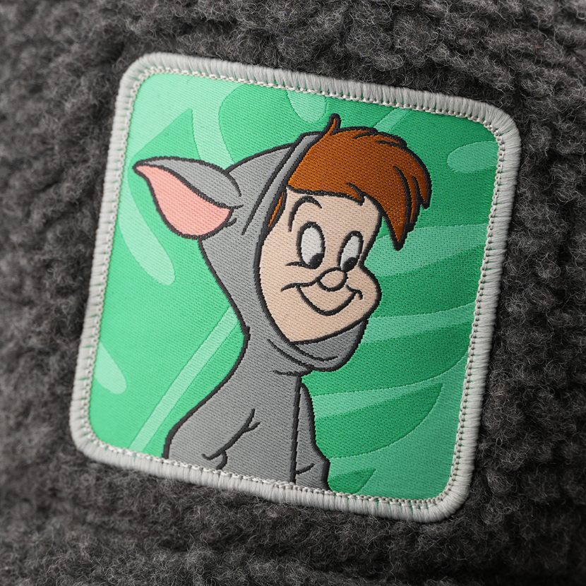 Woven patch of the First Twin from Disney's Peter Pan smiling in an animal costume against a leafy background, with a gray border, stitched onto the charcoal boucle-textured retro trucker cap.