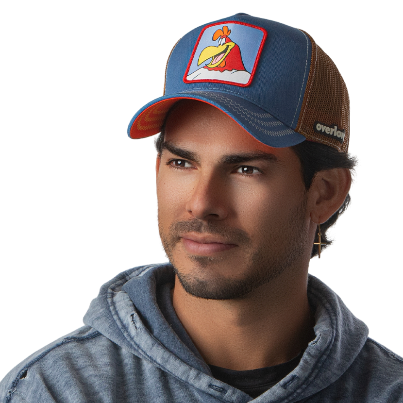 Man wearing a steel blue twill trucker cap with brown mesh featuring a woven patch of Foghorn Leghorn from Looney Tunes attached to the crown.