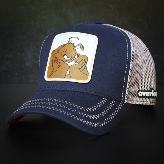 Navy Blue OVERLORD X Looney Tunes Marc Anthony the dog trucker baseball cap hat with khaki zig zag stitching. PVC Overlord logo.