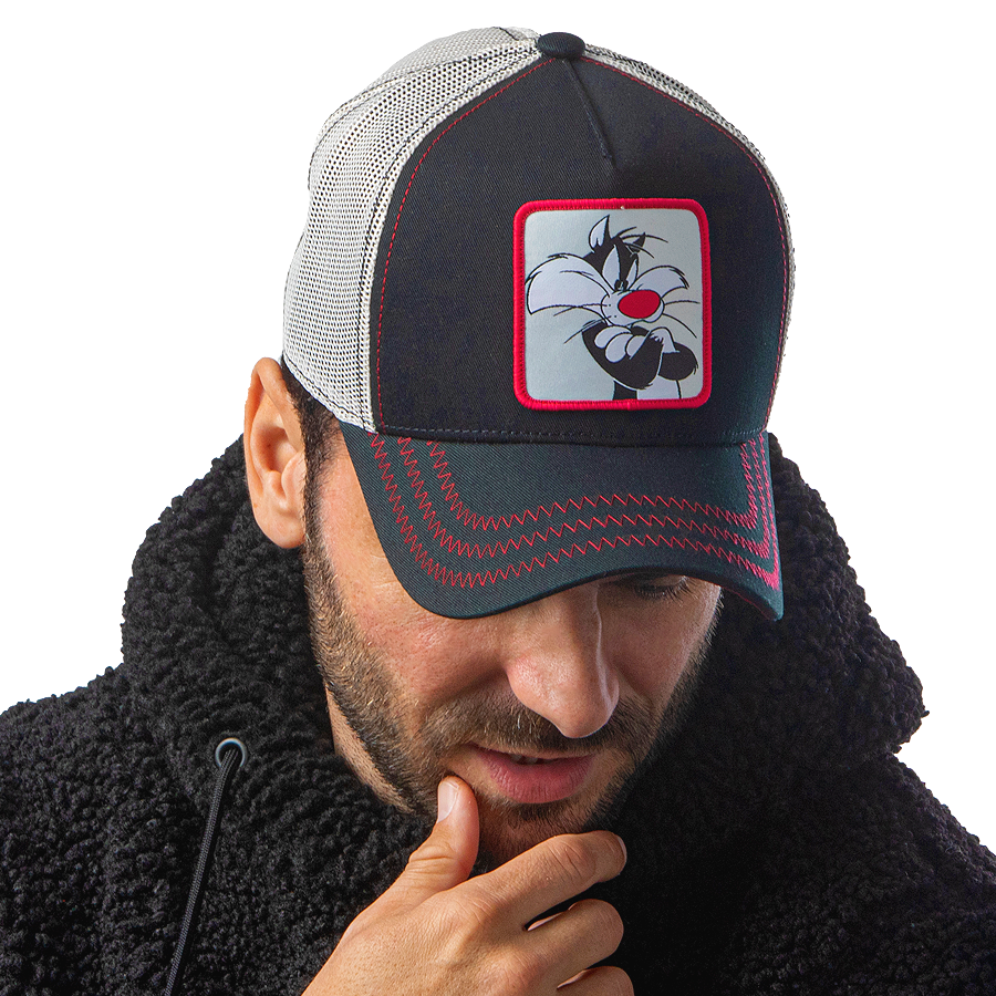 Man wearing black OVERLORD X Looney Tunes smug Sylvester the cat trucker baseball cap hat with red zig zag stitching. PVC Overlord logo.