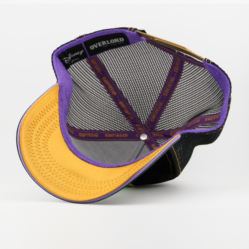 Underside of the Maleficent retro trucker cap showing a gold brim, Disney tag, black mesh crown, and purple Overlord taping.