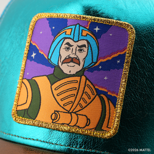 Woven patch of Man-At-Arms from Masters of the Universe in a blue helmet and orange armor, set against a starry purple sky background with gold border, stitched onto the metallic teal retro trucker cap.