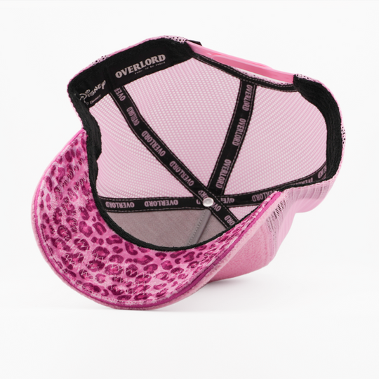 Underside of the Miss Piggy retro trucker cap, showing a leopard-print pink brim, a Disney tag, pink mesh crown, and black Overlord branded taping with pink text.