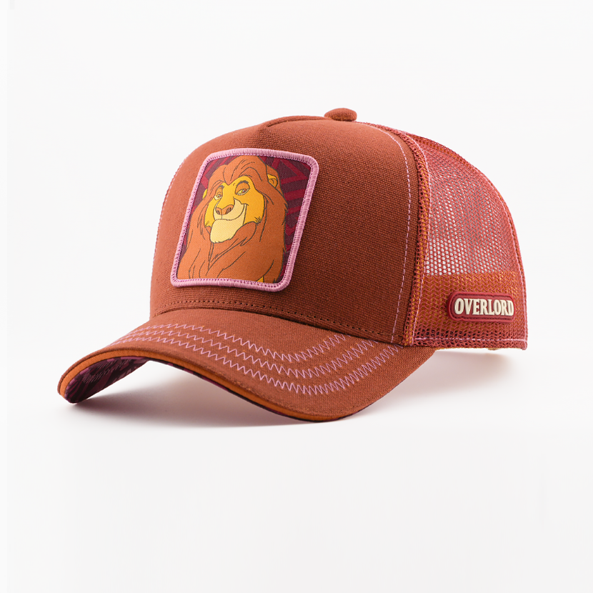Brown corduroy-textured retro trucker cap with a woven Mufasa from Disney's The Lion King patch on a dark red patterned background with a pink border, brown mesh back with Overlord logo.