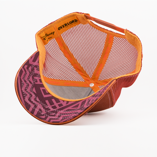 Underside of the Mufasa from Disney's The Lion King retro trucker cap showing a pink patterned brim with orange trim, brown mesh crown, Disney tag, and orange Overlord branded taping.