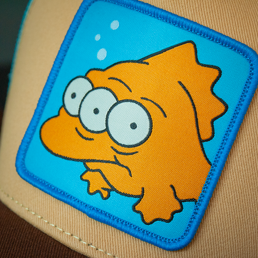 Tan and brown OVERLORD X The Simpsons Blinky the three-eyed fish trucker cap hat woven Overlord patch closeup.