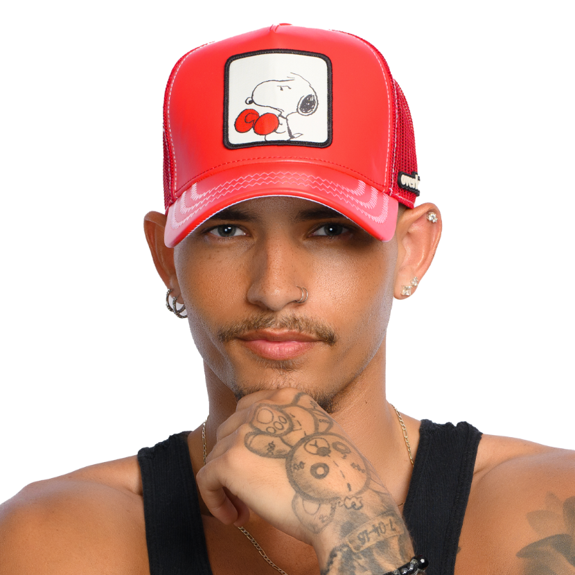 Man wearing a red faux leather trucker cap featuring a woven patch of Peanuts Boxing Snoopy attached to the crown.