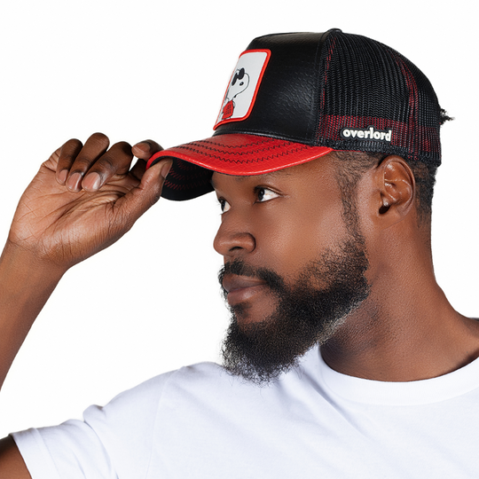 Man wearing black and red leather crocodile skin embossed trucker cap with black mesh featuring a woven patch of Joe Cool Snoopy from the Peanuts Comics attached to the crown.