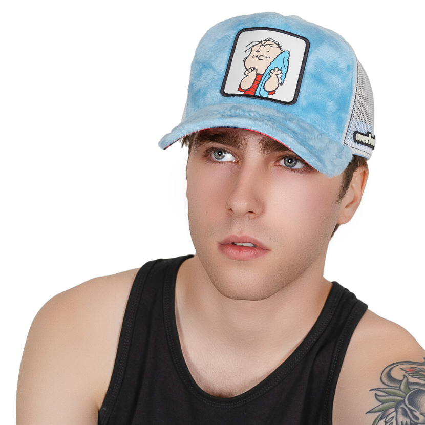 Man wearing light blue faux fur trucker cap with cream mesh featuring a woven patch of Linus from the Peanuts Comics attached to crown.